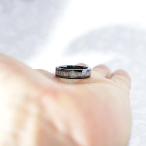 Może przedstawiać: Czarny i srebrny pierścionek z fakturowanym paskiem.