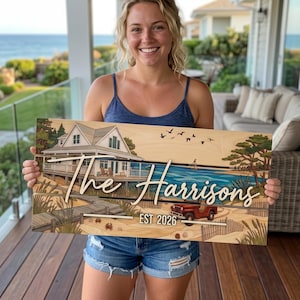 May include: A wooden sign depicting a beach house scene with the text "The Harrisons" and "EST 2026". The sign includes a red jeep, a pier, and a blue ocean. The sign is held by a person.