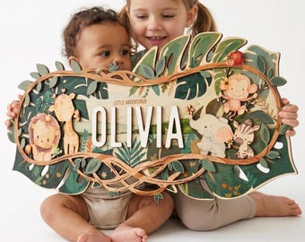 May include: A wooden name sign with a jungle theme, featuring the name "OLIVIA" in white letters. The sign is decorated with a lion, giraffe, monkey, elephant, and zebra. The sign is held by two children.