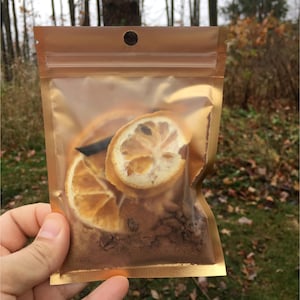 May include: A gold resealable pouch filled with dried orange slices, cinnamon sticks, and other spices. The pouch is clear and shows the contents inside.