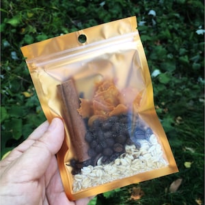 May include: A gold resealable pouch filled with a mix of ingredients, including cinnamon sticks, dried fruit, oats, and coffee beans.