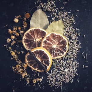 May include: Dried lavender flowers and dried citrus fruit slices on a dark gray background.