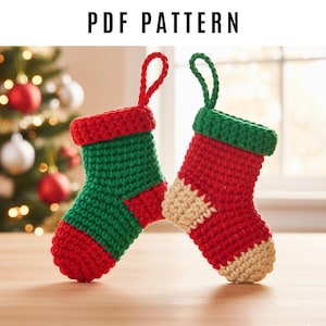 Peut inclure: Deux petits bas de Noël faits à la main, de couleurs rouge, verte et crème. Les bas sont crochetés avec une boucle pour les suspendre. Le texte "PDF PATTERN" est en haut de l'image.