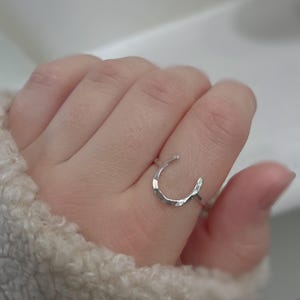 K&ouml;nnte beinhalten: Ein silberner Ring in Form eines Hufeisens. Der Ring ist texturiert und hat eine geh&auml;mmerte Oberfl&auml;che.