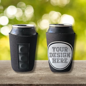 May include: Two black can coolers with a can inside. One cooler has a black leatherette patch with three vertical rectangles. The other cooler has a white oval with the text "YOUR DESIGN HERE".