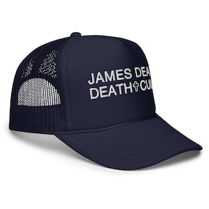 May include: A navy blue trucker hat with a white mesh back. The front of the hat has white embroidered text that reads "JAMES DEAN DEATH+CULTURE".