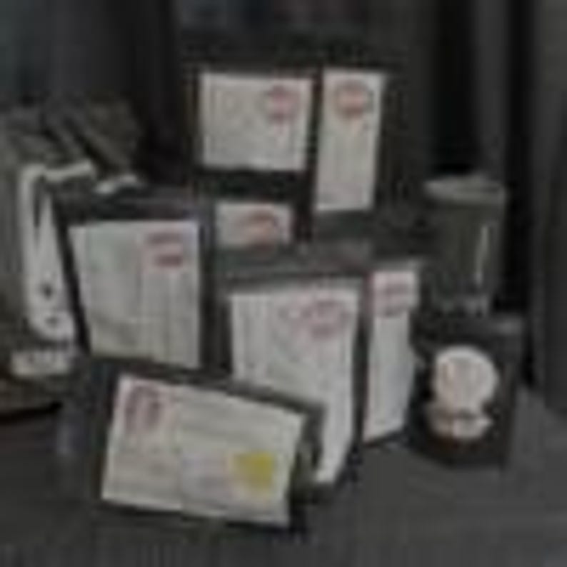 May include: A collection of sealed black pouches and bags, some with white labels and red circular stamps. The bags are arranged in a display, suggesting a variety of sizes and contents. The background is a dark, neutral color.