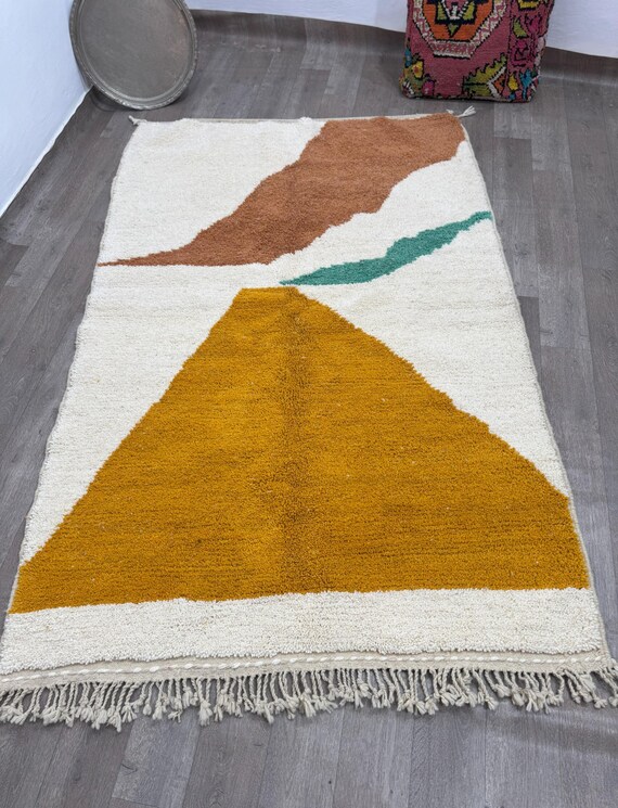 A hand-woven bohemian rug with mountain motifs and warm earthy tones adds a modern artistic touch to any space.