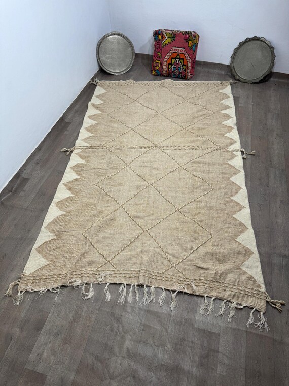 A traditional Moroccan rug, handcrafted from natural wool, with simple geometric Berber patterns and earthy colors that add a warm touch