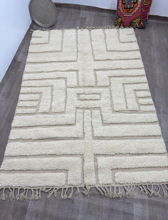 A traditional Moroccan rug with a raised geometric pattern in a soft cream color, adding a warm and modern touch to any space.