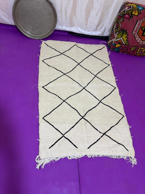 Handwoven Moroccan rug with colorful intersecting lines on natural wool – minimalist Berber design blending tradition with modern style.
