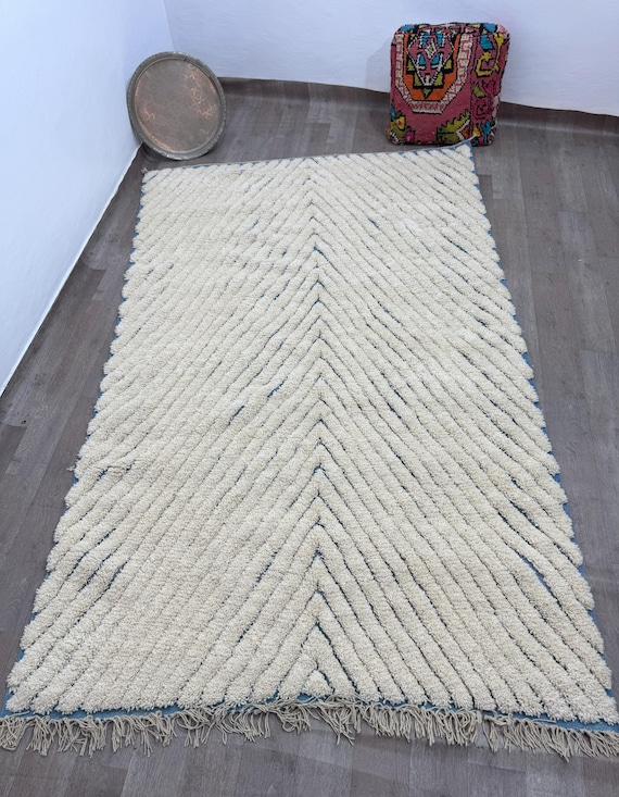 A modern Moroccan rug with a prominent pattern and a blue base adds warmth and elegance to any corner of your home.