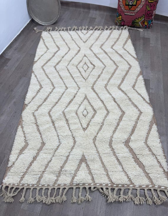 A modern Moroccan rug with a prominent pattern and a blue base adds warmth and elegance to any corner of your home.