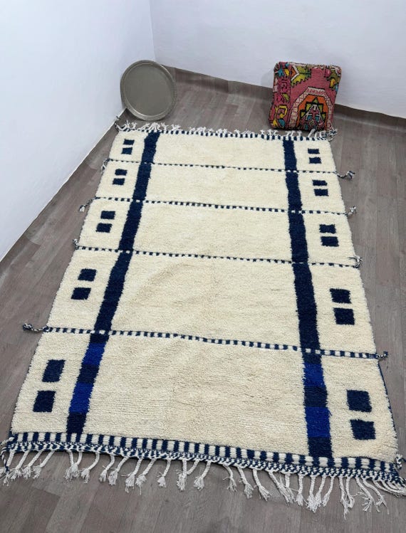 A simple and elegant handmade Berber rug made of natural wool in cream and dark blue - a unique traditional decorative piece.