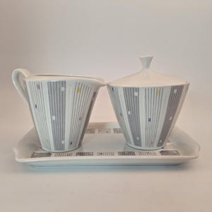 May include: A white ceramic creamer and sugar bowl set with a gray and white geometric pattern. The set includes a matching tray.