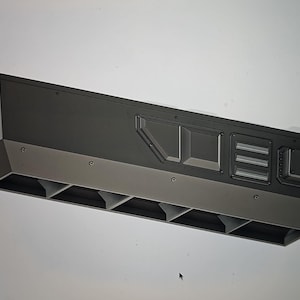 May include: A black rectangular metal box with a series of vents on the bottom and a rectangular opening on the top. The box has a series of small holes on the top and sides.