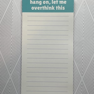 May include: A rectangular notepad with a teal header that reads "hang on, let me overthink this." The notepad has lined pages and a light blue border at the bottom. The background is a white and gray geometric pattern.
