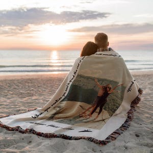 May include: A couple sits on a beach wrapped in a woven blanket with a photo of them printed on it. The blanket has the text "When you realize you want to spend the rest of your life with somebody, you know you've found something special." printed on it.