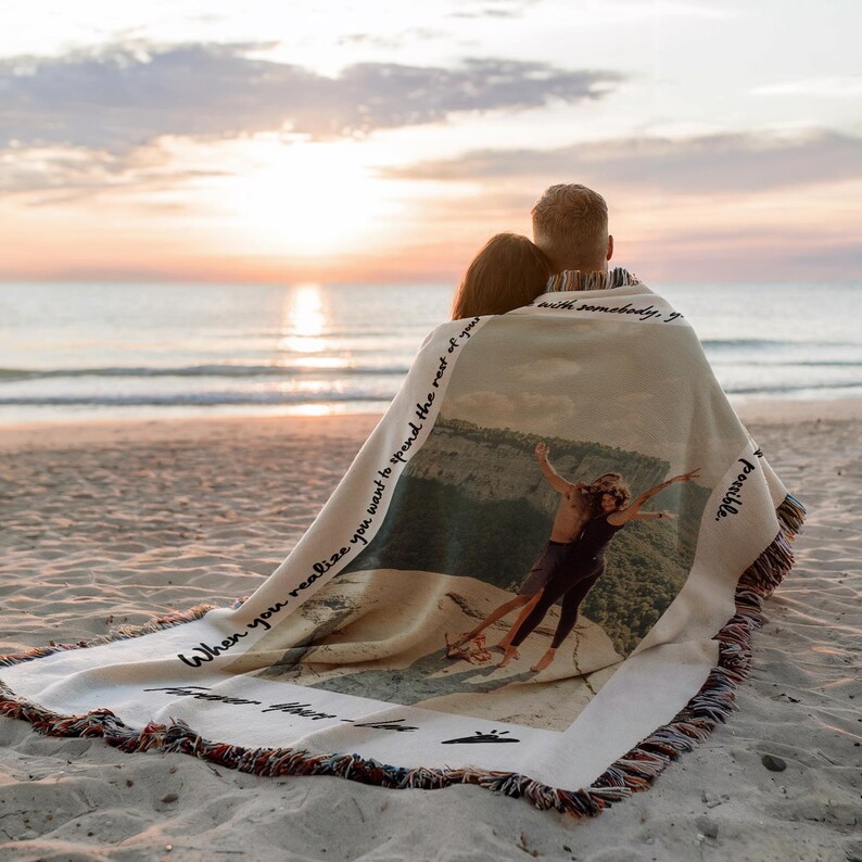 May include: A couple sits on a beach wrapped in a woven blanket with a photo of them printed on it. The blanket has the text "When you realize you want to spend the rest of your life with somebody, you know you've found something special." printed on it.