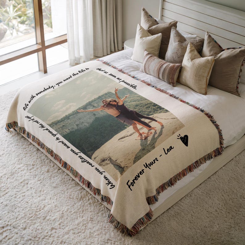 May include: A woven tapestry throw blanket with a photo of a couple standing on a cliff with their arms outstretched. The blanket has a fringe border and the text "life with somebody, you want the life to start as soon as possible. When you realize you want to spend the rest of your  Forever Yours - Lea" is printed on the blanket.