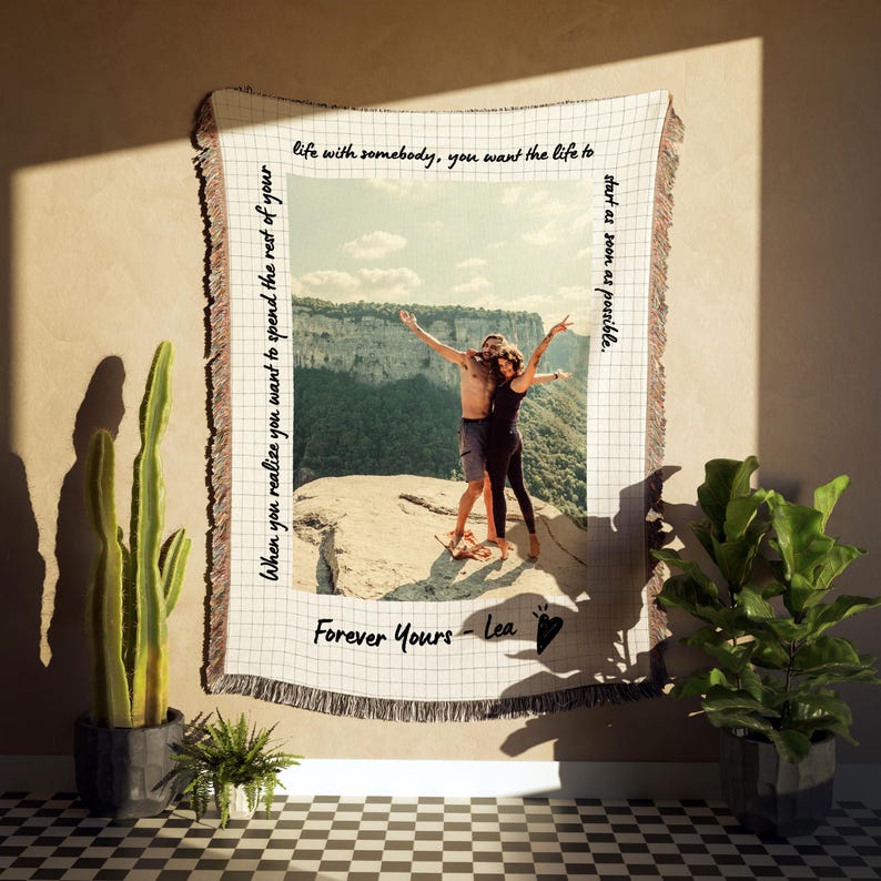 May include: A woven tapestry with a photo of a couple standing on a cliff. The tapestry has a grid pattern and the text "When you realize you want to spend the rest of your life with somebody, you want the life to start as soon as possible. Forever Yours - Lea" is written on it.