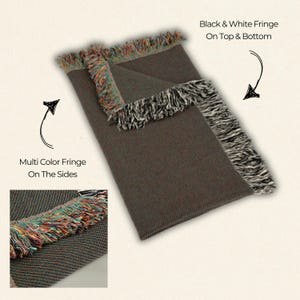 May include: A brown woven throw blanket with black and white fringe on the top and bottom and multi-colored fringe on the sides.