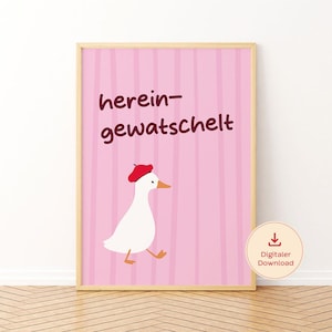 Könnte beinhalten: Ein gerahmter Wandkunstdruck mit einer weißen Gans, die ein rotes Barett trägt, auf einem hellrosa Hintergrund mit vertikalen Streifen. Der Text "herein-gewatschelt" steht in dunkelbraunen Buchstaben über der Gans. Ein Symbol zeigt einen digitalen Download.