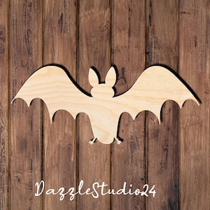 May include: A wooden bat cutout with outstretched wings, perfect for Halloween decor. The bat is light brown and has a detailed design. The background is a rustic wooden surface. The text "DazzleStudio24" is at the bottom.