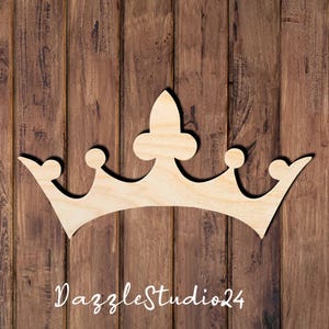 May include: A light-colored wooden crown cutout featuring a central fleur-de-lis point flanked by two smaller rounded points and two outer curved tips. The text DazzleStudio24 is printed in white script at the bottom of the wooden crown shape.