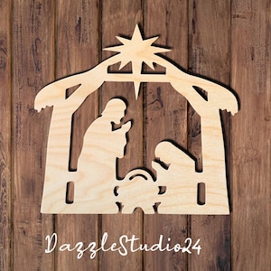 May include: A light-colored wooden cutout of a nativity scene featuring a stable structure, a star at the top, and silhouettes of two figures kneeling beside a manger. The text DazzleStudio24 is printed in white script at the bottom of the image.