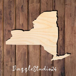 May include: A wooden cutout of the state of New York, painted in a light wood color. The cutout is placed on a brown wooden background.