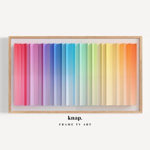 May include: A framed artwork featuring a spectrum of colors, from red to orange, arranged in vertical stripes. The artwork is in a light wood frame, with the text "knap. FRAME TV ART" at the bottom.