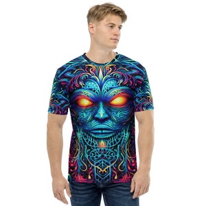 May include: A blue, black, and pink t-shirt with a psychedelic, tribal-inspired face design. The face has glowing orange eyes.