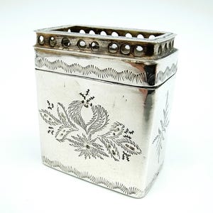May include: A silver rectangular box with a decorative floral design and a pierced top. The box is made of silver and has a polished finish.