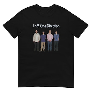 以下が含まれることがあります： 前面に白い文字で「I <3 One Direction」とプリントされた黒いTシャツ。シャツの中央には、カジュアルな服装をした5人の男性が写っています。