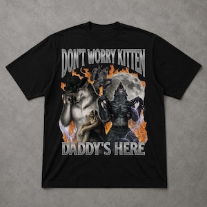 May include: Black t-shirt with a graphic featuring three werewolves, a full moon, and flames. Text on the shirt reads "DON'T WORRY KITTEN" above "DADDY'S HERE" in a silver, distressed font.