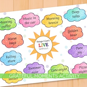 May include: A white paper with colorful cloud-shaped text bubbles. The bubbles contain phrases like "Morning coffee," "Warm hugs," and "Pizza nights." A sun graphic in the center reads "Things I Can't LIVE Without..." and the bottom reads "GRATEFUL MOMENTS ACTIVITY."