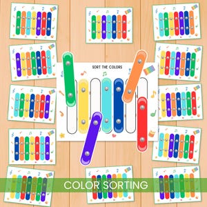 Może przedstawiać: Edukacyjna gra do sortowania kolorów z kolorowymi elementami przypominającymi ksylofon. Gra zawiera planszę do sortowania z napisem "SORT THE COLORS" oraz kilka kart z ilustracjami ksylofonu. Widoczny jest również napis "COLOR SORTING".