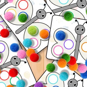 May include: Butterfly-shaped cards with colorful circles and matching pom-poms in various colors, including red, orange, green, blue, and pink. The cards have a gray butterfly design with a white background. Educational toy.