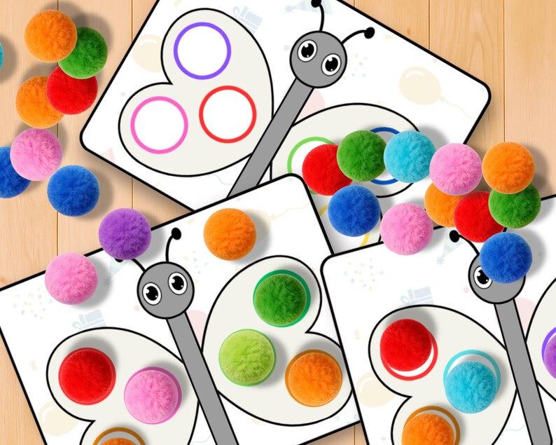 May include: Educational butterfly-themed game with colorful pom-poms. The game features butterfly-shaped cards with colored circles, designed for matching pom-poms by color. The pom-poms are in various colors, including orange, red, green, blue, and pink.