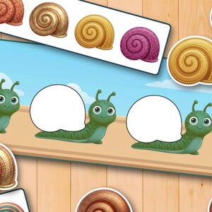 May include: A digital educational game featuring green cartoon snails with blank white speech bubbles on their backs. Various spiral snail shells in shades of gold, brown, and purple are arranged around the snails for matching purposes.