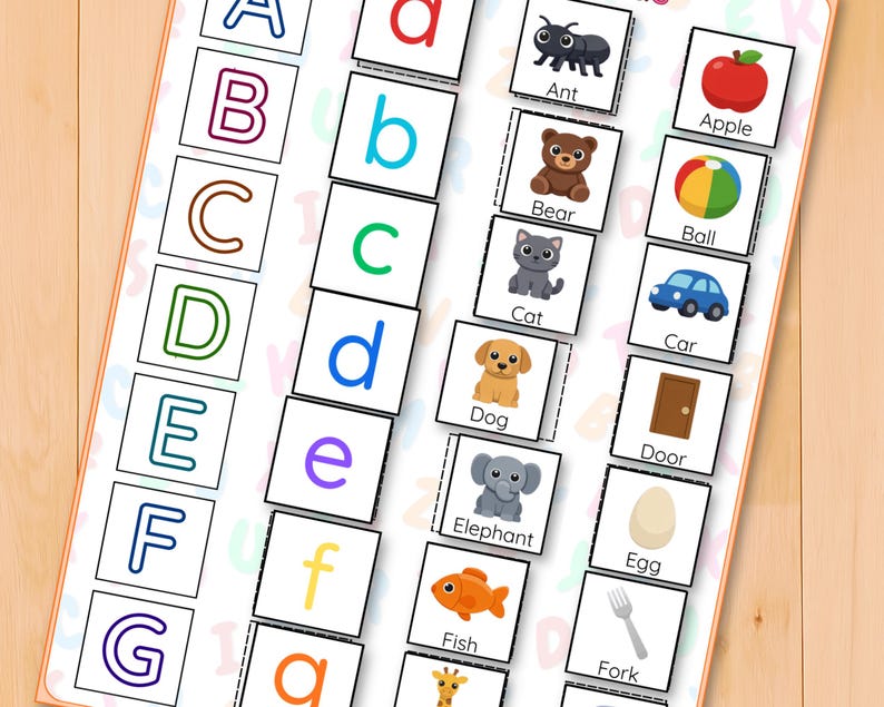 May include: A set of educational flashcards with the alphabet and related images. The cards show uppercase and lowercase letters, alongside pictures of an ant, apple, bear, ball, cat, car, dog, door, elephant, egg, fish, and fork. The cards are on a light wood surface.