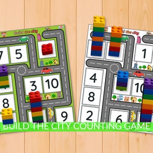Op de afbeelding: Twee kleurrijke telspelborden met een stadsthema. Elk bord heeft een wegenkaartontwerp met cijfers en ruimtes voor bouwstenen. De tekst "Build the City Counting Game" staat onderaan, met kleurrijke bouwstenen op elk bord.