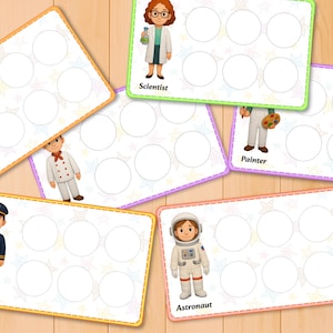 May include: Colorful educational cards featuring various professions: Builder, Scientist, Pilot, Astronaut, and Painter. Each card has a picture of the profession and a set of blank circles. The cards are on a wooden surface.