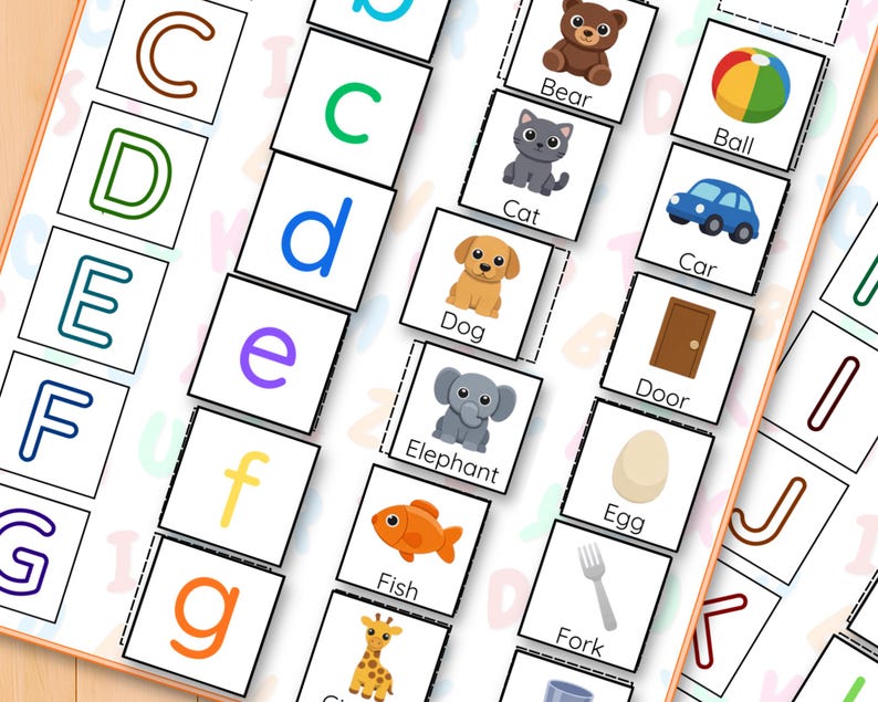 May include: Alphabet flashcards for education, featuring colourful letters and corresponding illustrations. Includes images of a bear, cat, dog, elephant, and fish. The cards are arranged on a light-coloured surface.
