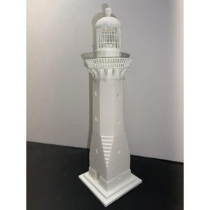 Könnte beinhalten: Ein weißes 3D-gedrucktes Modell eines Leuchtturms mit detailliertem Design. Der Leuchtturm hat einen hohen, zylindrischen Turm mit einem kleinen, kuppelförmigen Dach und einer Laterne oben. Der Turm ist mit einer Reihe von Fenstern und einem Geländer oben verziert.