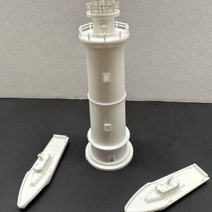 Könnte beinhalten: Ein weißes Plastikmodell eines Leuchtturms mit einem weißen Plastikmodell eines Bootes auf jeder Seite.
