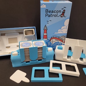 May include: A blue and white board game called "Beacon Patrol" with a lighthouse and boat on the box cover. The game includes a blue and white card holder, a white card holder with three compartments, and a white and blue card holder with two compartments.
