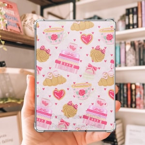 May include: A rectangular tablet case featuring a repeating pattern of pink teacups with roses, stacked pink gift boxes, golden croissants, heart-shaped cookies, and small pink bows on a white background. The case has silver metallic corner protectors.