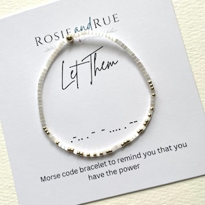 May include: White beaded bracelet with gold beads spelling out "Let Them" in Morse code. The card reads "Morse code bracelet to remind you that you have the power."